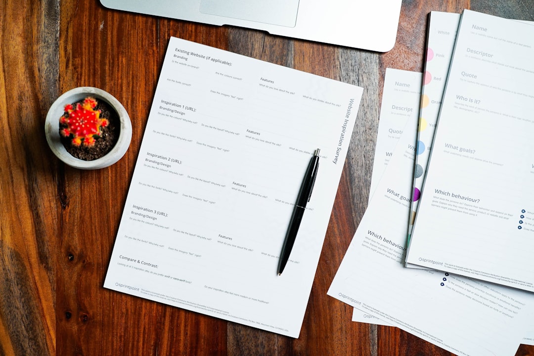 a wooden table topped with papers and a pen - Photo by 2H Media on Unsplash