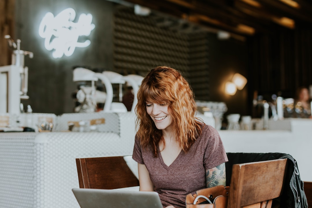 woman sitting on brown wooden chair while using silver laptop computer in room - Photo by Brooke Cagle on Unsplash