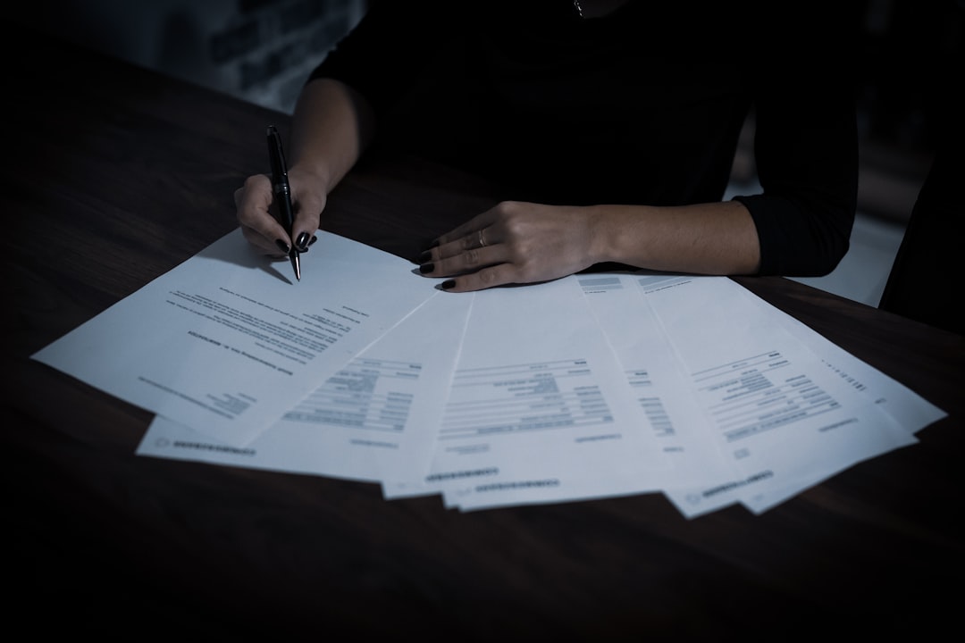 a woman sitting at a table with lots of papers - Photo by Dimitri Karastelev on Unsplash