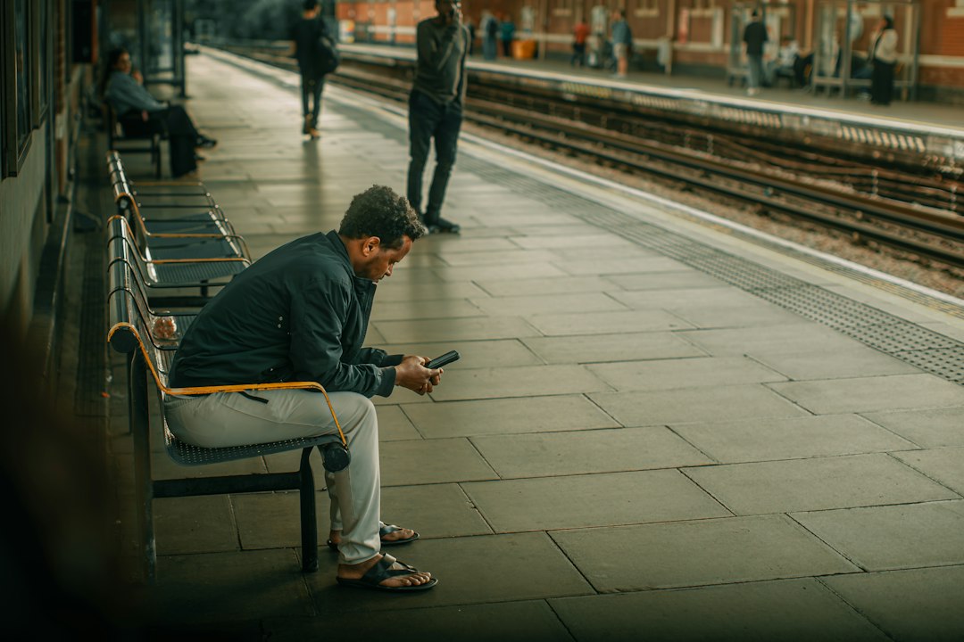 A man sitting on a bench looking at his cell phone - Photo by Gilley Aguilar on Unsplash