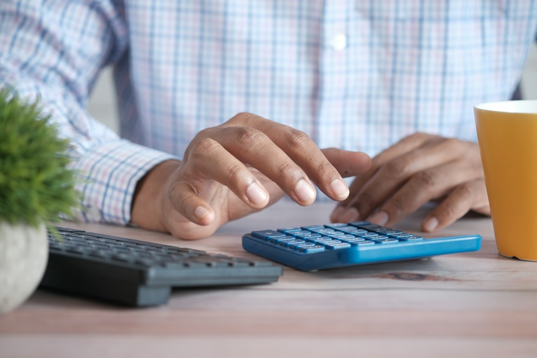 person using calculator at desk with coffee mug - Photo by Towfiqu barbhuiya on Unsplash
