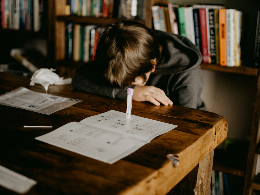 boy in gray hoodie reading book on brown wooden table - Photo by Annie Spratt on Unsplash