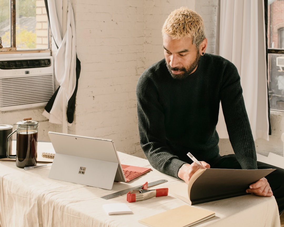 a man sitting at a table with a laptop and notebook — Photo by M. Cooper on Unsplash