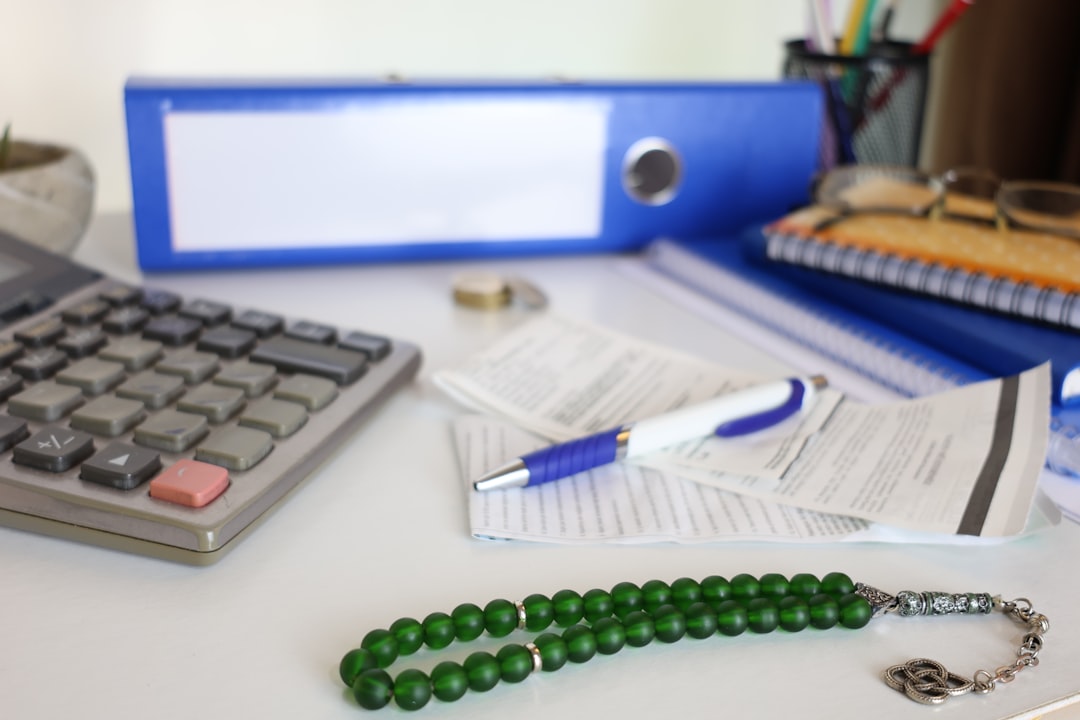 Desk with calculator, papers, and prayer beads. - Photo by Cht Gsml on Unsplash