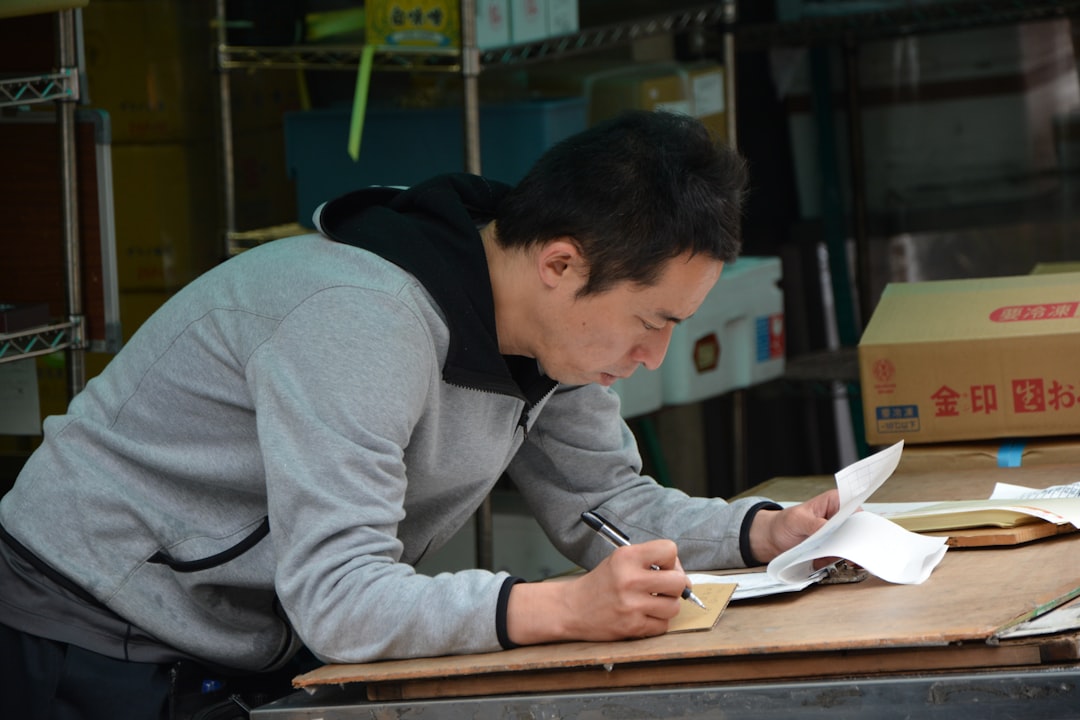 man in gray hoodie writing on white paper - Photo by Beth Macdonald on Unsplash