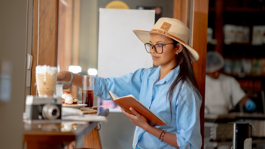 A woman wearing a hat and reading a book - Photo by Shane Ryan Herilalaina on Unsplash