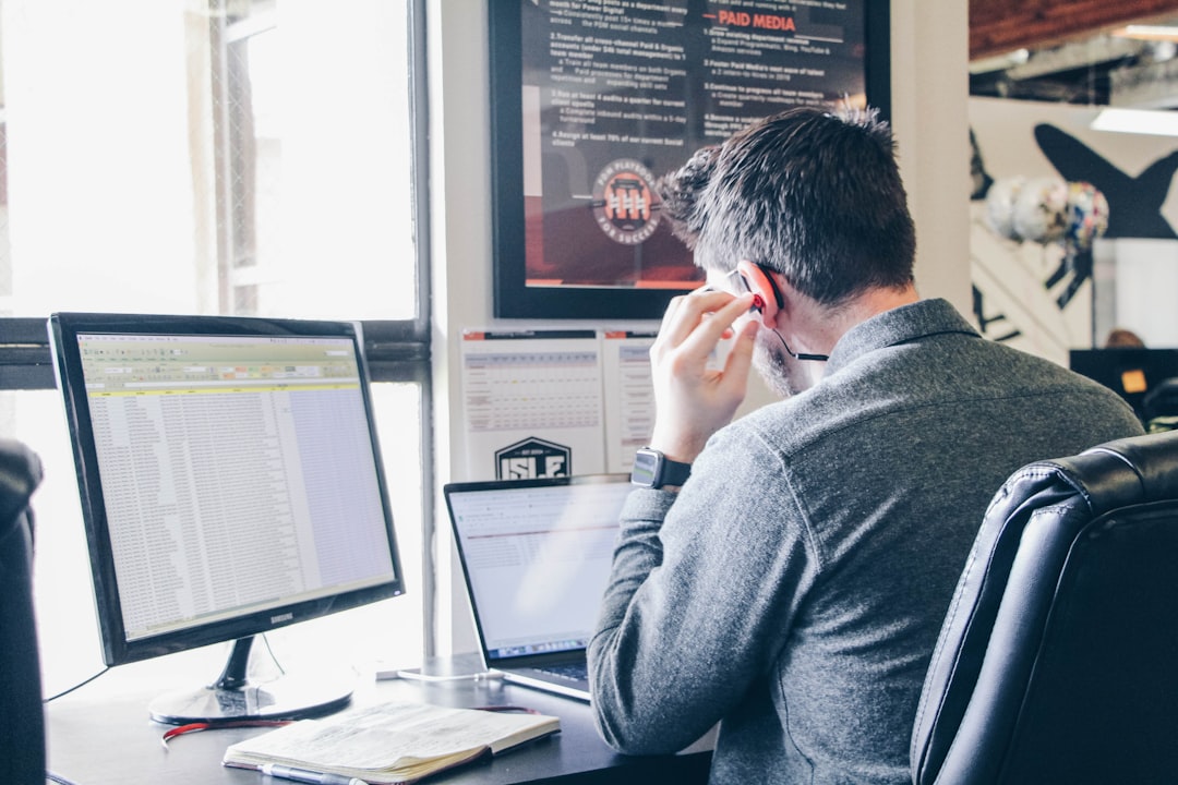 man in blue long-sleeved shirt sitting at table using laptop - Photo by Power Digital Marketing on Unsplash