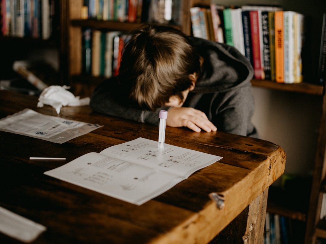boy in gray hoodie reading book on brown wooden table - Photo by Annie Spratt on Unsplash