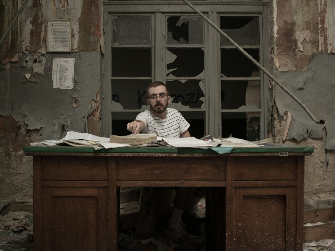 man in white and black striped shirt sitting beside brown wooden table - Photo by Anita Jankovic on Unsplash