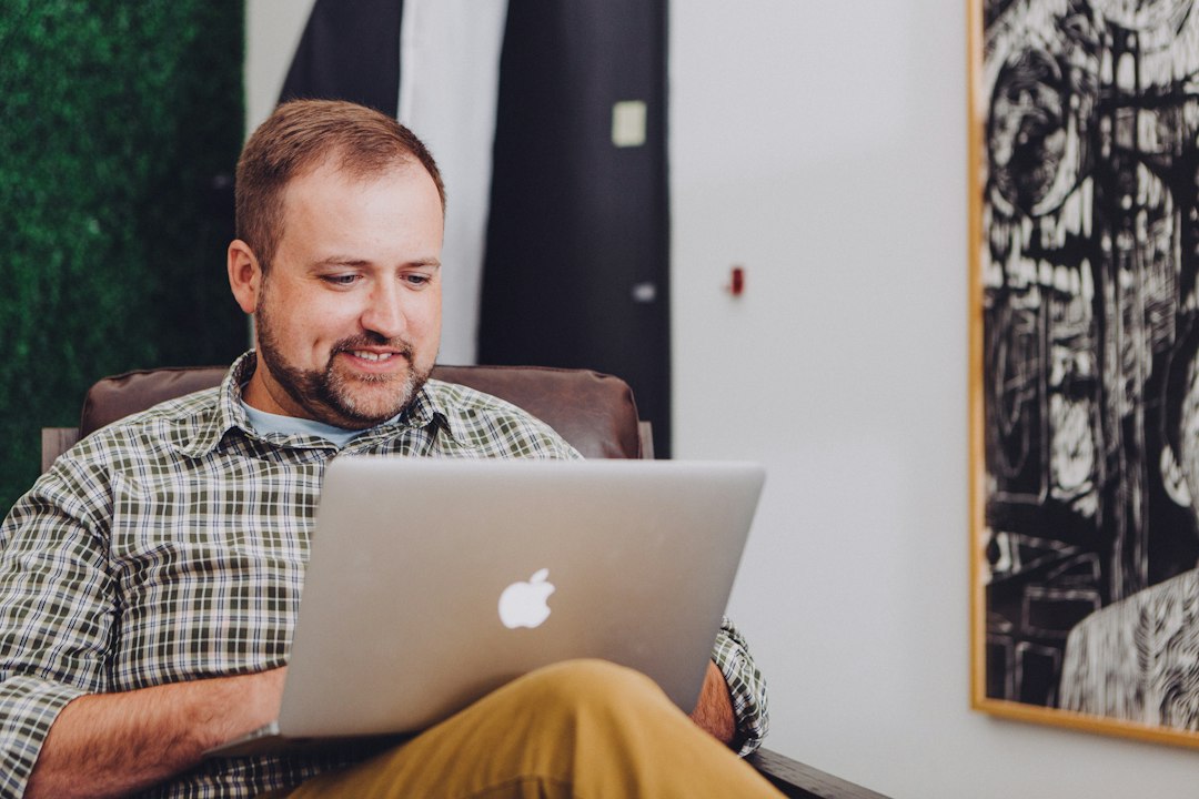 man smiling and using MacBook - Photo by Jud Mackrill on Unsplash