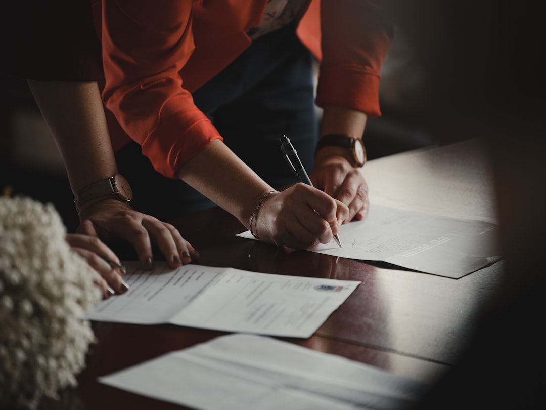 person in orange long sleeve shirt writing on white paper - Photo by Romain Dancre on Unsplash