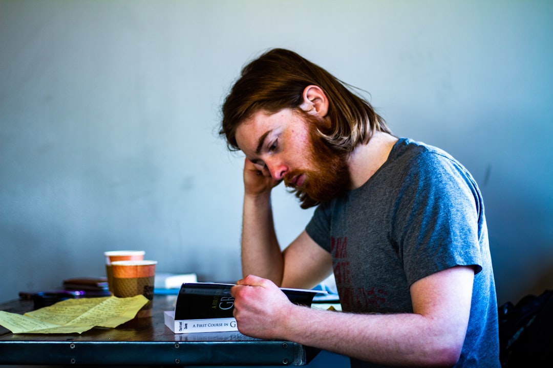 woman in blue shirt sitting by the table - Photo by Sam Battaglieri on Unsplash