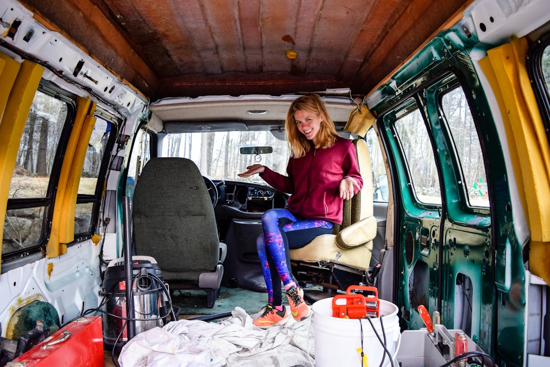 woman in red long sleeve shirt and blue denim jeans sitting on green van - Photo by hilary bird on Unsplash