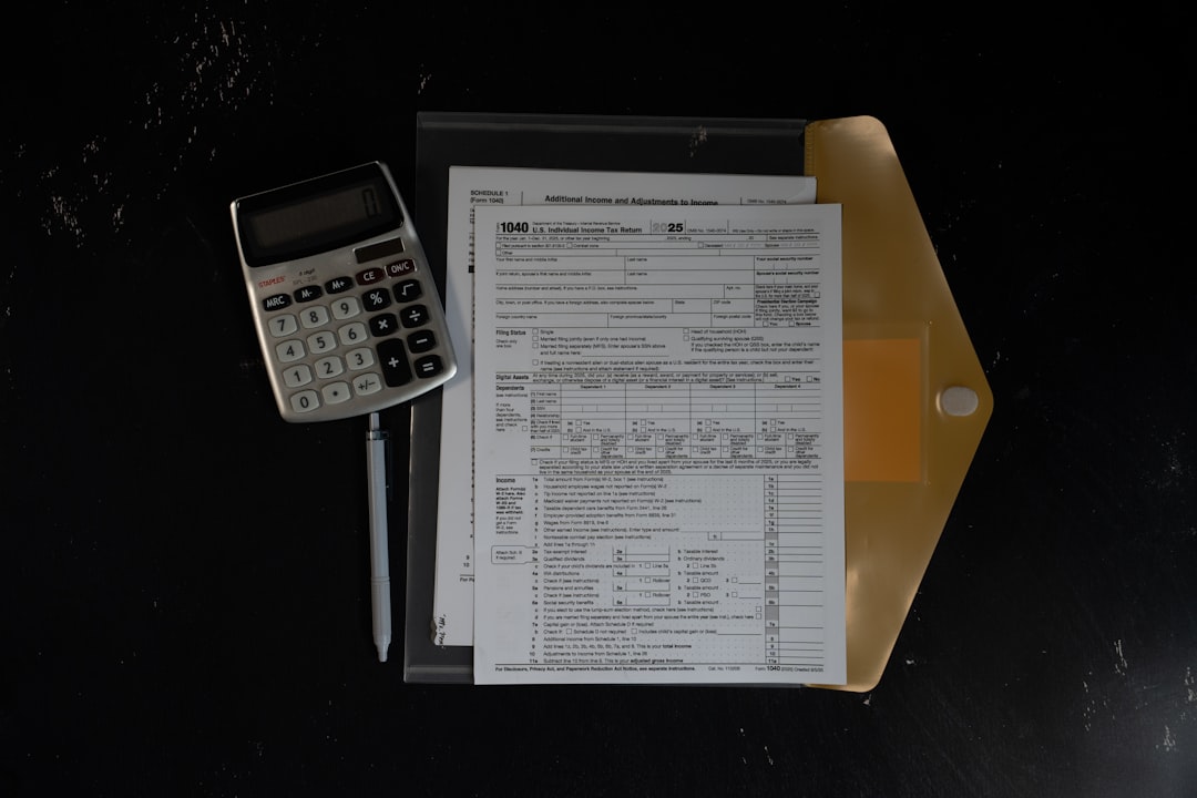 Calculator and papers in a folder on a dark surface — Photo by Kelly Sikkema on Unsplash