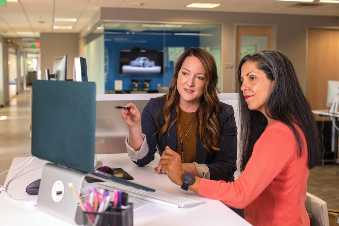 two women sitting at a table looking at a computer screen - Photo by LinkedIn Sales Solutions on Unsplash