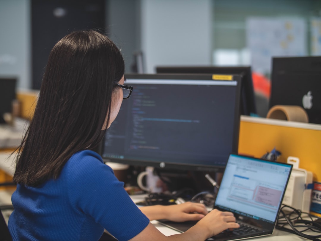 woman using black laptop computer near turned on flat screen computer monitor - Photo by Mimi Thian on Unsplash
