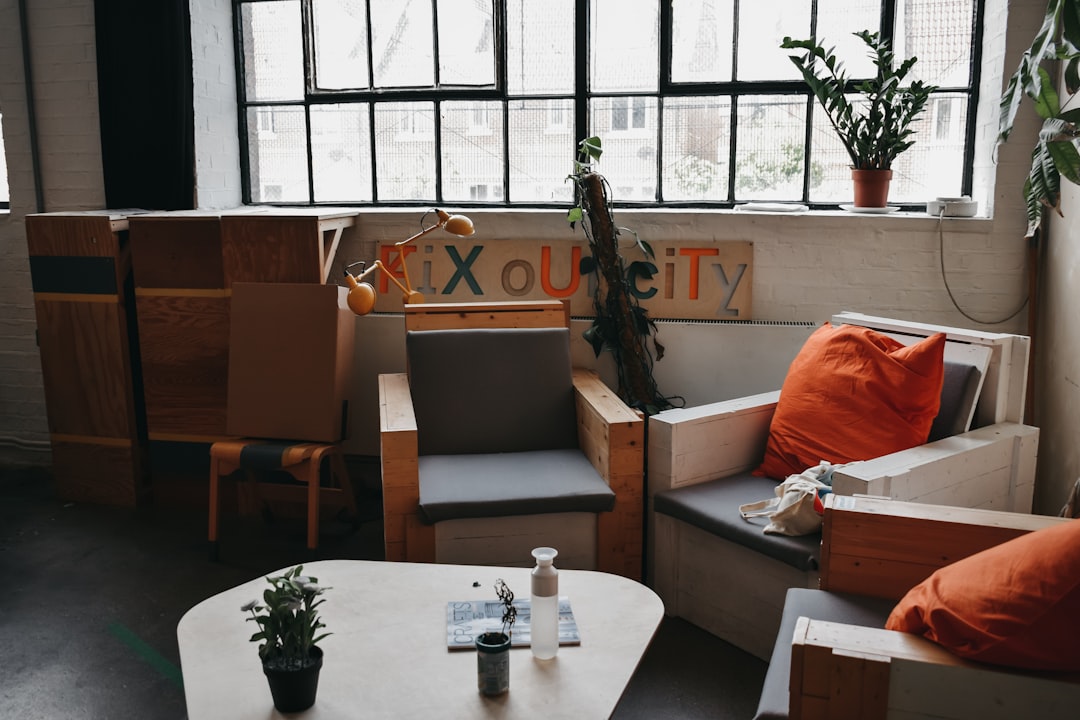 orange throw pillows on sofa armchairs near wooden wooden coffee table — Photo by Darya Tryfanava on Unsplash