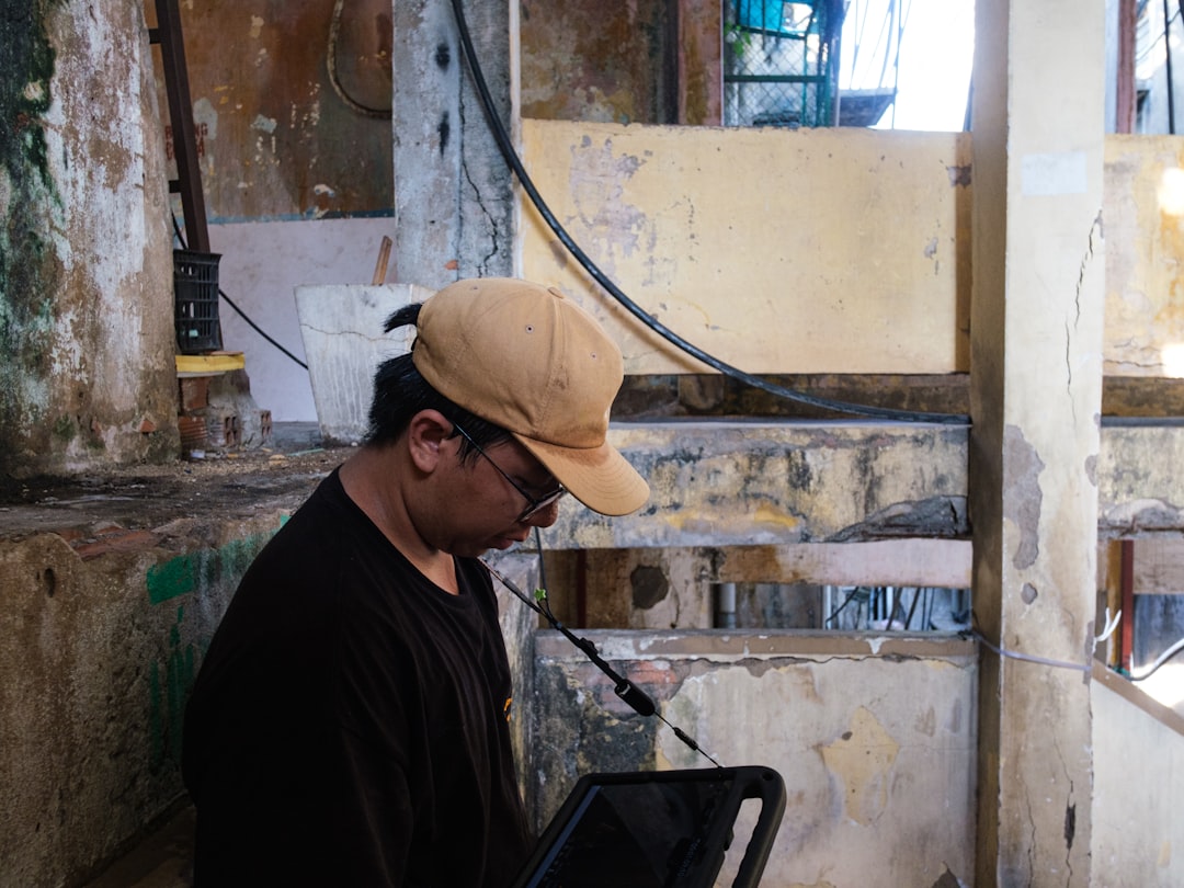 Man in tan cap looking down in a dilapidated structure. - Photo by Tri Vo on Unsplash