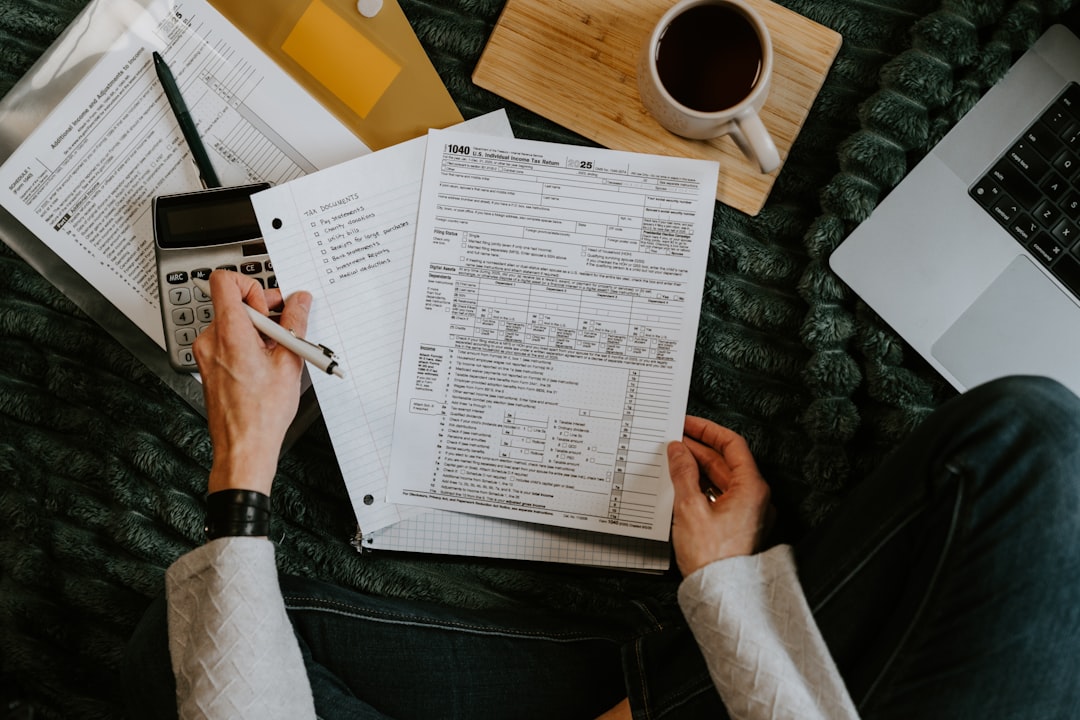 Person reviewing documents with calculator and laptop. — Photo by Kelly Sikkema on Unsplash