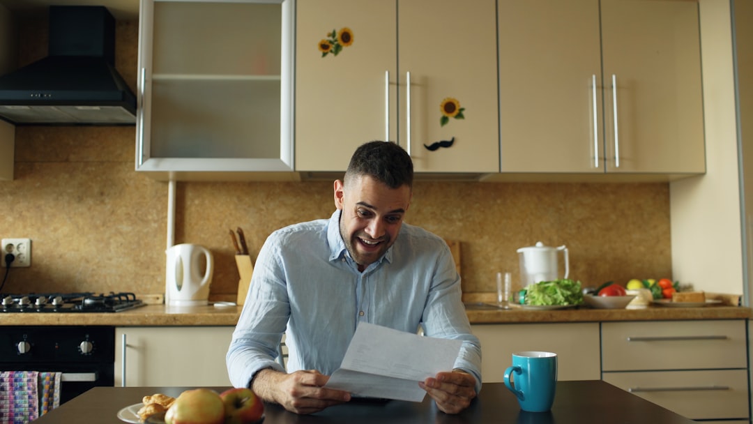 Man reading a letter at a kitchen table - Photo by Vitaly Gariev on Unsplash
