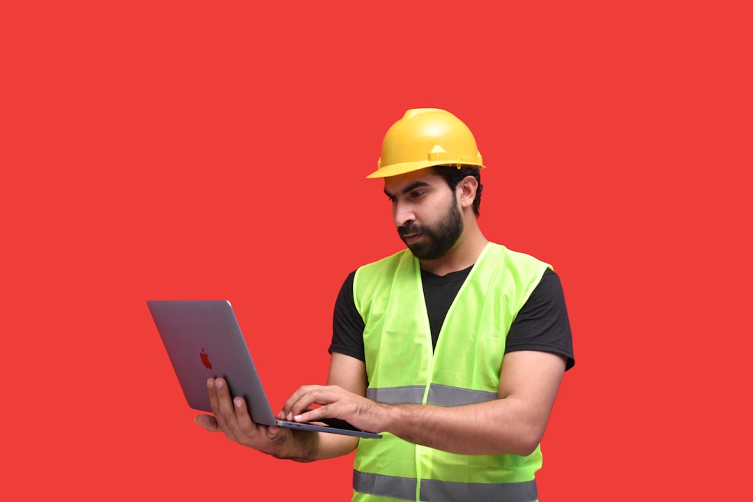 a man in a yellow hard hat holding a tablet - Photo by Fotos on Unsplash